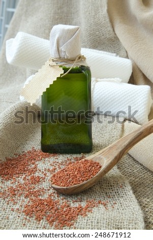 Garden cress seeds oil in the bottle. An olive wood spoon full of cress seeds in front on a sackcloth