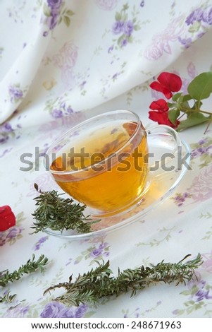 A glass cup of summer savory herbal tea. Summer savory twigs in the background