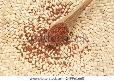 Garden cress seeds in the olive wood spoon on a woven surface