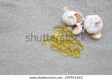 Garlic oil in the capsules on a sackcloth. Free space for a text.