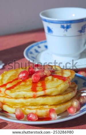 Winter breakfast: cheese pancakes with red topping and pomegranate grains.Closeup