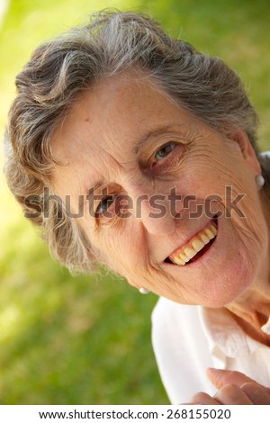 A happy smiling old woman between 70 and 80 years old is sitting in the garden