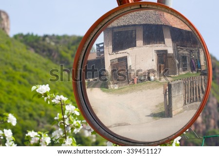 Traffic mirror at complicated countryside street. Old house is reflected in the mirror