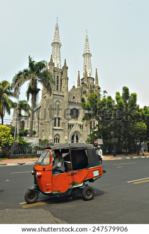 Jakarta, Indonesia, September 19, 2012 : Three wheel vehicle locally known as \'Bajai\' pass by a cathedral in Jakarta on September 19, 2012. Bajai is the second favourite transportation in Indonesia.