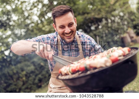 Summertime fun.Man cooking meat on barbecue for summer family dinner in the backyard of the house.