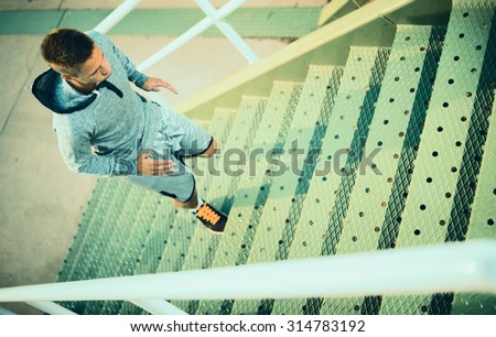 Man runner running on stairs in city, sport training. Young male jogger athlete training and doing workout outdoors in city. Fitness and exercising outdoors urban environment.