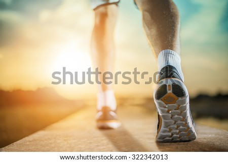 Close up shot of runner\'s shoes.A person running outdoors on a sunny day. Only the feet are visible. The person is wearing black running shoes.Exercise, fitness and healthy lifestyle.