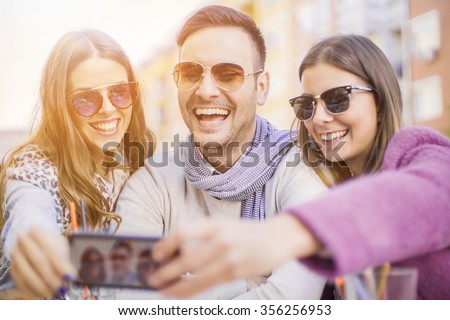 Group of young people laughing and doing a selfie in cafe.It is a nice day with sunshine.