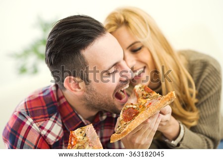Portrait of an happy couple.They are laughing and eating pizza and having a great time.