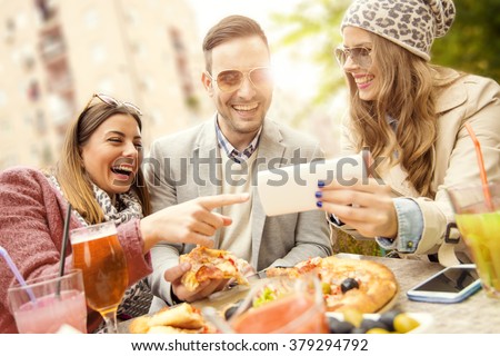 Young group of laughing people eating pizza and having fun
