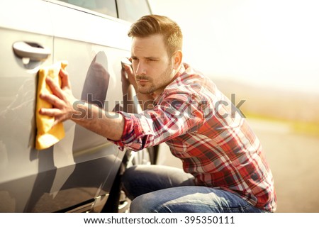 Young man cleaning his car outdoors.Man with a microfiber wipe the car polishing