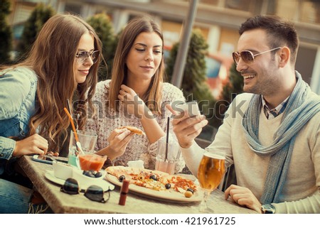 Young group of laughing people eating pizza and having fun.They are enjoying eating and drinking together.