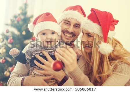 Happy family in the room with the Christmas tree.The family is enjoying in the holidays.They are celebrating their first Christmas together.
