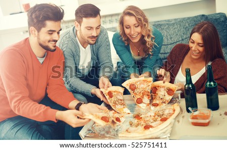 Friends eating pizza. They are having party at home, eating pizza and having fun.