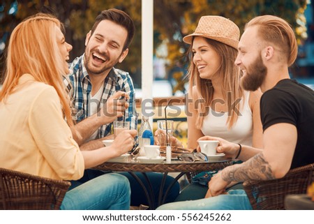 Friends having a great time in cafe.Friends smiling and sitting in a coffee shop, drinking coffee and enjoying together.