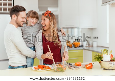 Happy young family preparing lunch in the kitchen and enjoying together.