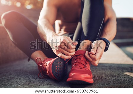 Man tying jogging shoes.A person running outdoors on a sunny day.