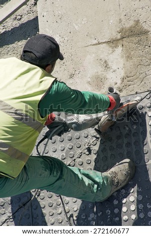 street construction worker repairing sidewalks with electric hand saw in the city
