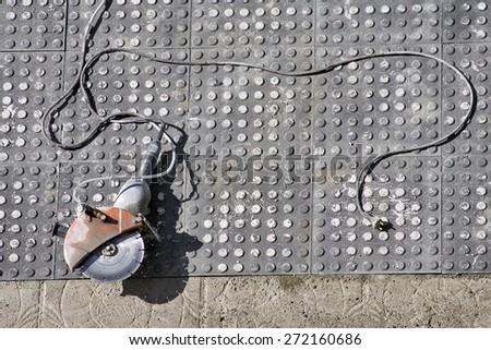 street worker repairing sidewalks with electric hand saw in the city