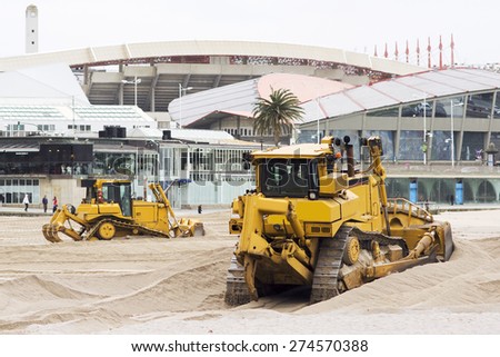 yellows excavators on the city  beach working sand moving in Corunna Spain