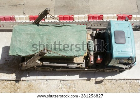 construction rubble truck with cargo container with plastic protection in street city