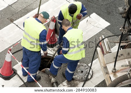 utility service company workers moves the manhole cover to cleaning the sewer line for clogs
