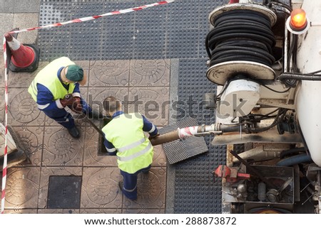 utility service company worker cleaning the city street  with water pressure