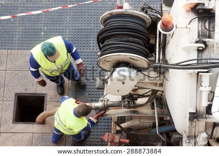 utility  workers moves the manhole cover to cleaning the sewer line for clogs