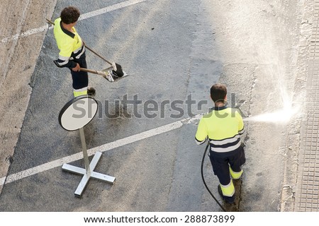 utility service company man  worker cleaning the street  with water pressure at city