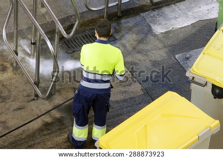 utility service company man  worker cleaning the street with water pressure at city