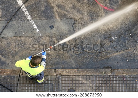 a  worker cleaning the city streets with water pressure