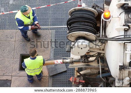 utility service company  workers  moves the manhole cover to cleaning the sewer line for clogs