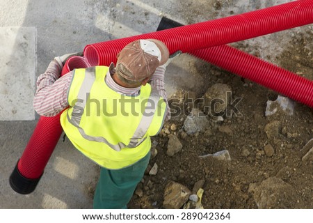 construction worker  carrying a broken pipe  in the  city  street