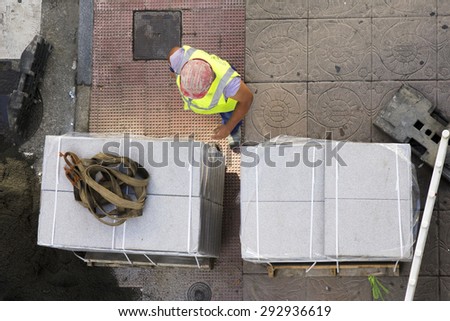 construction truck bringing pallets of tiles to repair the sidewalks on city street