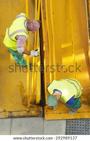 construction workers carrying a mobile metal walkway  in the street city