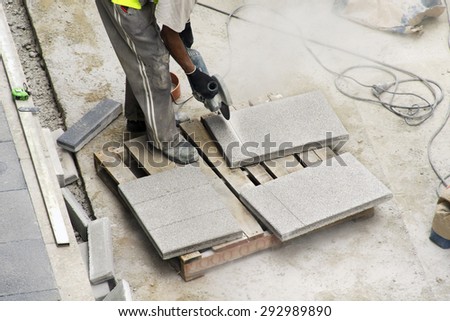 construction  worker cutting tiles with electric grinder for repairing sidewalks