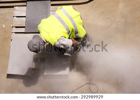 construction  worker cutting tiles with electric grinder for repairing sidewalks