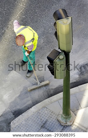 construction worker sweeping up on rough concrete in city street  using a large broom