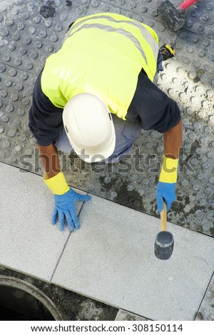 mason construction worker to repair  tiles slabs in  the sidewalk  at road in  the street city
