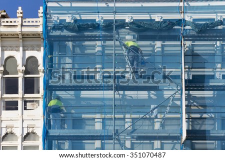 construction workers in  scaffolding  on the building  facade for restore, repair and renovate