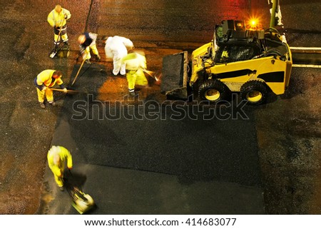 construction workers for repairing  the crosswalk in the city road with skid steer loader vehicle at night