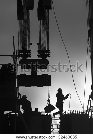 Construction workers outdoors back lit by the setting sun.