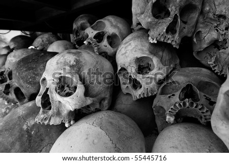 Black and white photo of the skulls of torture victims resting in a stupa at the Killing Fields outside of Phnom Penh, Cambodia.