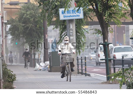 KAGOSHIMA CITY, JAPAN - JUNE 3: Cyclists cover their faces with masks to protect from ash which blanketed the city after an eruption of the volcano Sakurajima June 3, 2010 in Kagoshima City, Japan.