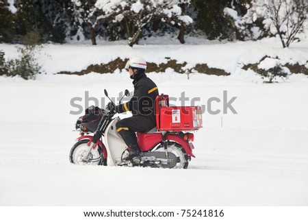 KAGOSHIMA CITY, JAPAN - JANUARY 1: Japan Post employee on a motorcycle delivers mail after a very rare heavy snowstorm which crippled the city for days. Kagoshima City, Japan, January 1, 2011.