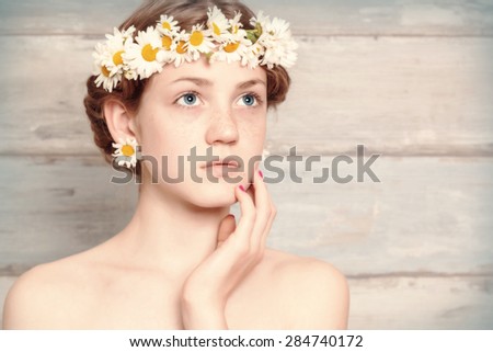 Beauty Model Girl with a chamomile wreath on a head. Beautiful Joyful teen girl with freckles.Wooden background.Vintage style