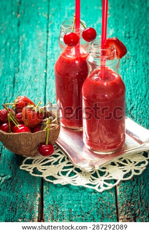fresh strawberry and cherries smoothie on a wooden background. Summer detox drink and refreshment organic concept.Vintage filter.