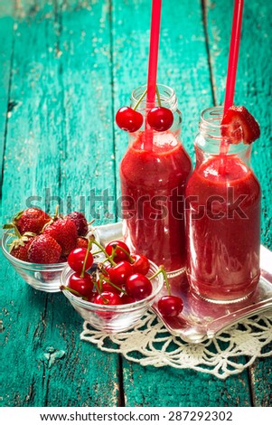 fresh strawberry and cherries smoothie on a wooden background. Summer detox drink and refreshment organic concept.Vintage filter.