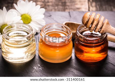 Honey in jar with honey dipper on black stone background