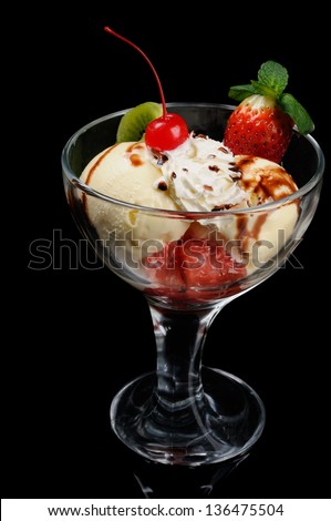 Tasty ice cream decorated by fruits on black background